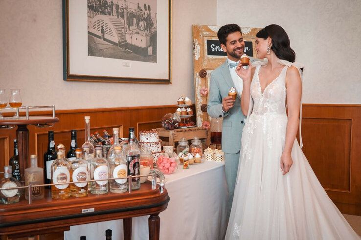 Bridal couple enjoying cupcakes at a festively decorated bar with spirits at the ATLANTIC Hotel Wilhelmshaven.