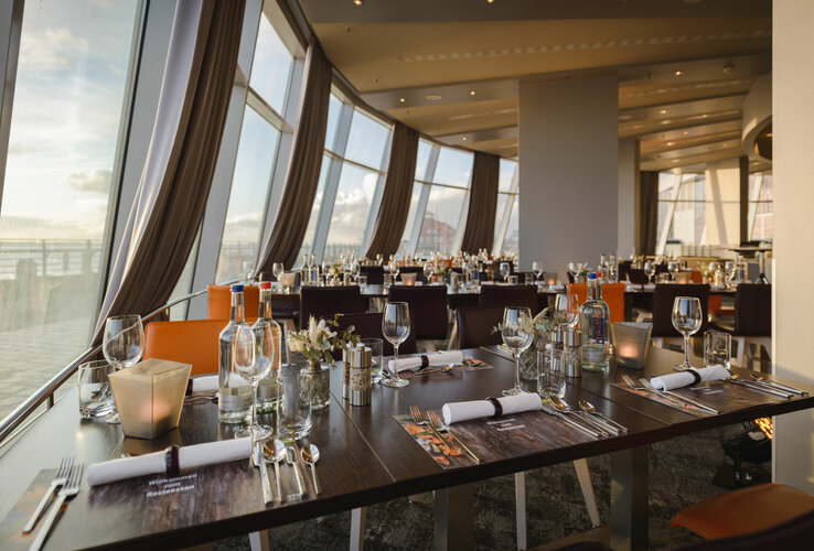 Modern restaurant with set tables and panoramic windows in the ATLANTIC Hotel Sail City, Bremerhaven.