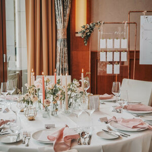 Eleganter Hochzeitstisch im ATLANTIC Hotel Wilhelmshaven mit Blumen, Kerzen und rosa Servietten dekoriert.