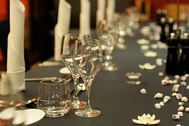 Elegantly laid table with glasses, white napkins and shell decorations at the ATLANTIC Hotel Kiel.