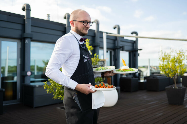 A friendly waiter serves food on the roof terrace of Bar Deck 8 Kiel