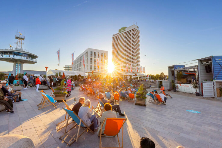Sonnenuntergang, Menschen entspannen in Liegestühlen auf einer Terrasse.