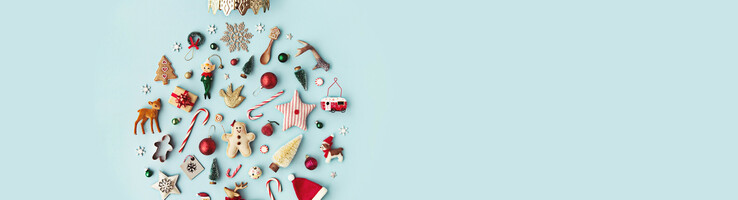 Weihnachtsschmuck und Kekse formen eine Kugel auf hellblauem Hintergrund.