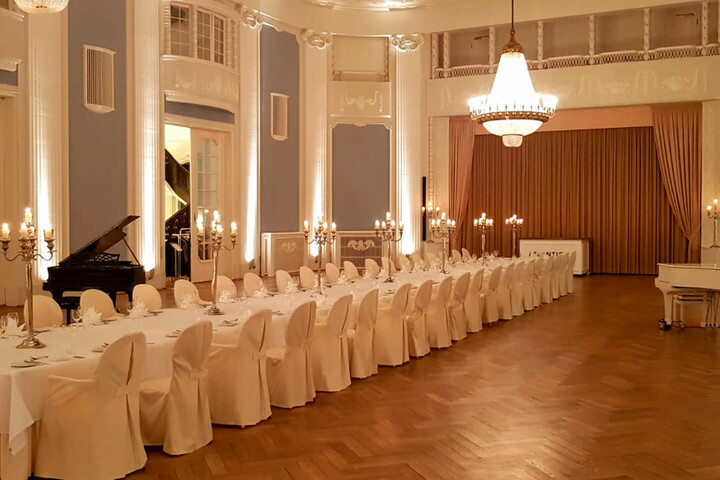 Eleganter Festsaal im ATLANTIC Grand Hotel Travemünde mit gedeckter Tafel, Kerzenständern und Kronleuchter.