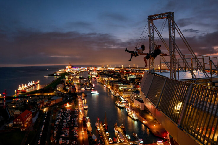 Zwei Personen die auf der High Swing auf dem ATLANTIC Hotel Sail City Schaukeln. KI Mockup