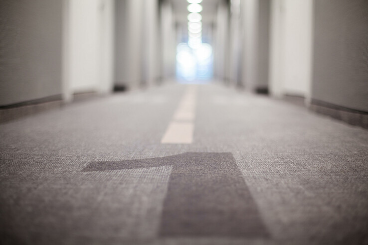 Hallway in the ATLANTIC Hotel Airport Bremen with carpeting and central line, doors on both sides, in blur.