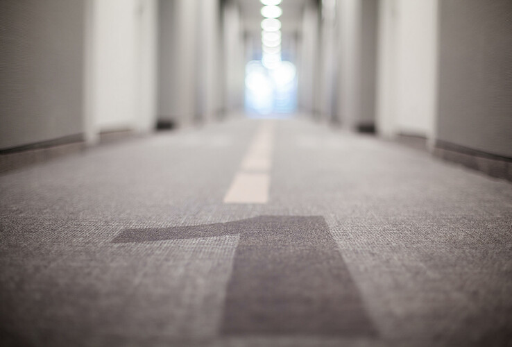 Hallway in the ATLANTIC Hotel Airport Bremen with carpeting and central line, doors on both sides, in blur.
