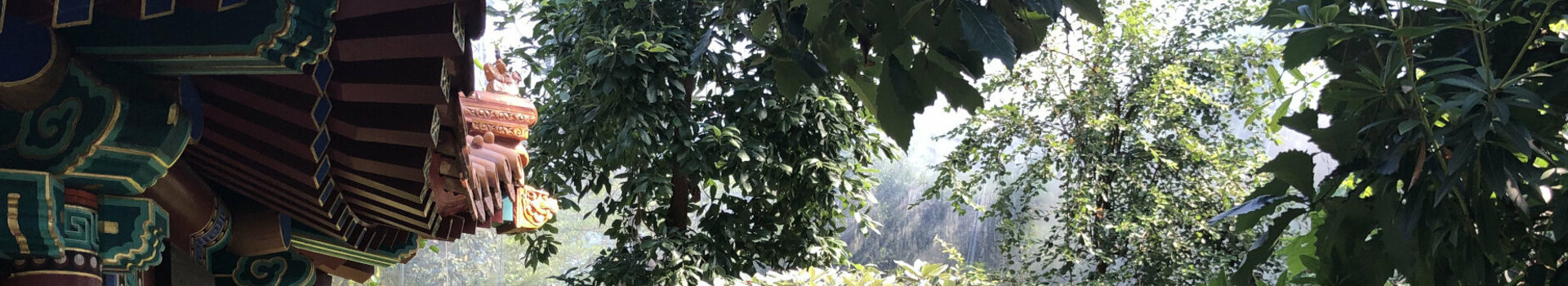 Traditional pavilion next to a lush, green garden path with flowers and benches.