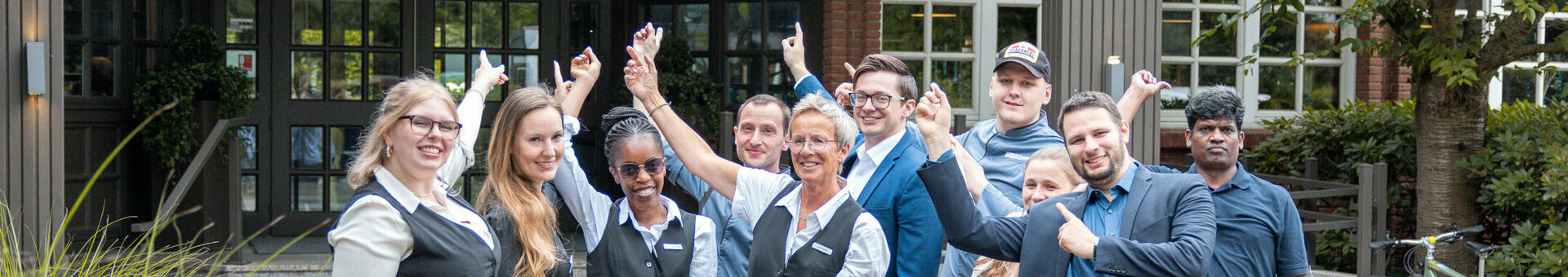 Hotel team in front of the entrance to the ATLANTIC Hotel Landgut Horn Bremen, smiling and friendly.
