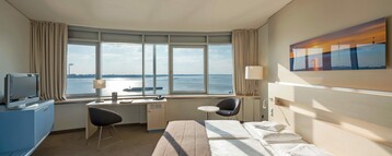 Interior view of a Deluxe Room with a double bed in the ATLANTIC Hotel SAIL City in Bremerhaven 