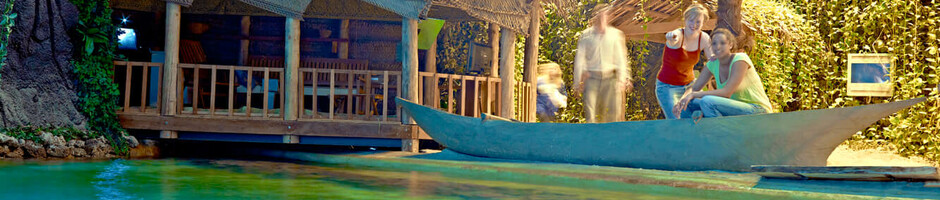 Tropischer Innenbereich mit Strohhütte, Palmen und Boot im ATLANTIC Hotel Sail City, Bremerhaven.