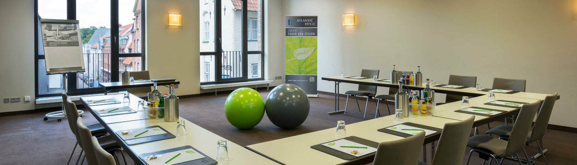 Modern conference room at the ATLANTIC Hotel Lübeck with U-shaped seating, flipchart and large windows.