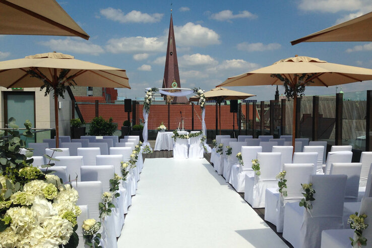 Rooftop wedding location with white chairs, flowers and parasols at the ATLANTIC Grand Hotel Bremen.