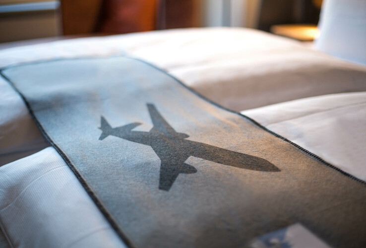 Business Zimmer im ATLANTIC Hotel Airport Bremen Bett mit grauer Decke, Flugzeugmotiv; modernes Zimmer im ATLANTIC Hotel Airport Bremen.