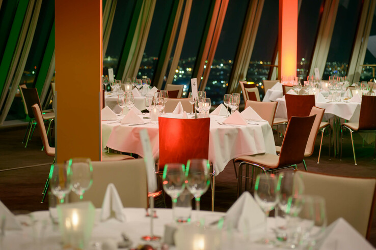 Elegant restaurant in the ATLANTIC Hotel Sail City with set tables and a panoramic view of the city lights.