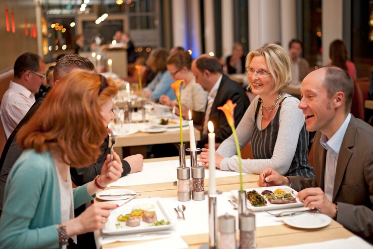 Gäste genießen ein Abendessen im stilvollen Restaurant des ATLANTIC Hotel Kiel, bei Kerzenschein und eleganter Atmosphäre.