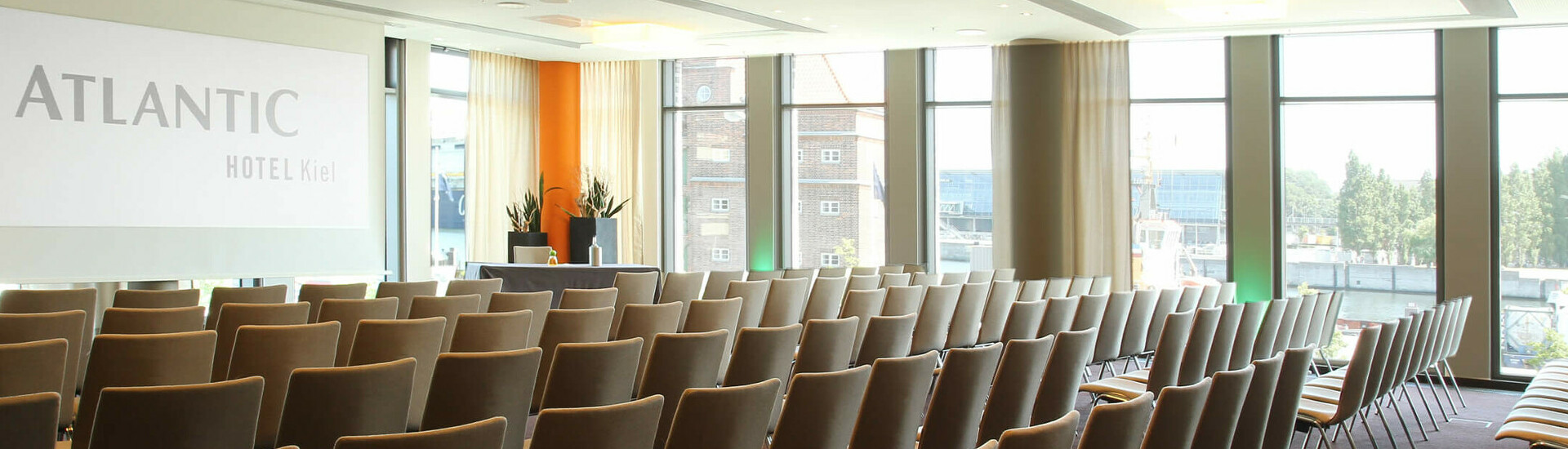 Modern conference room at the ATLANTIC Hotel Kiel with rows of chairs and large windows.