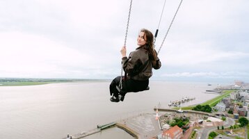 Frau schaukelt über der Aussichtsplattform auf dem ATLANTIC Hotel Sail City.