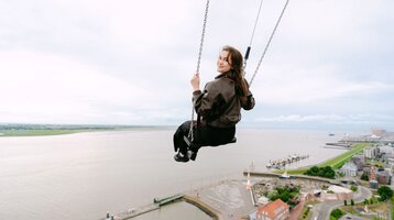 A woman is swinging above the viewing platform at the ATLANTIC Hotel Sail City.