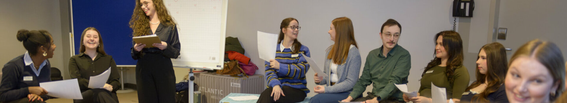 The trainees sit in a large circle of chairs while planning the trainee day.