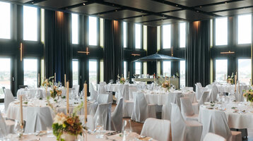 Eleganter Bankettsaal im ATLANTIC Hotel Heidelberg mit gedeckten Tischen und großen Fenstern.