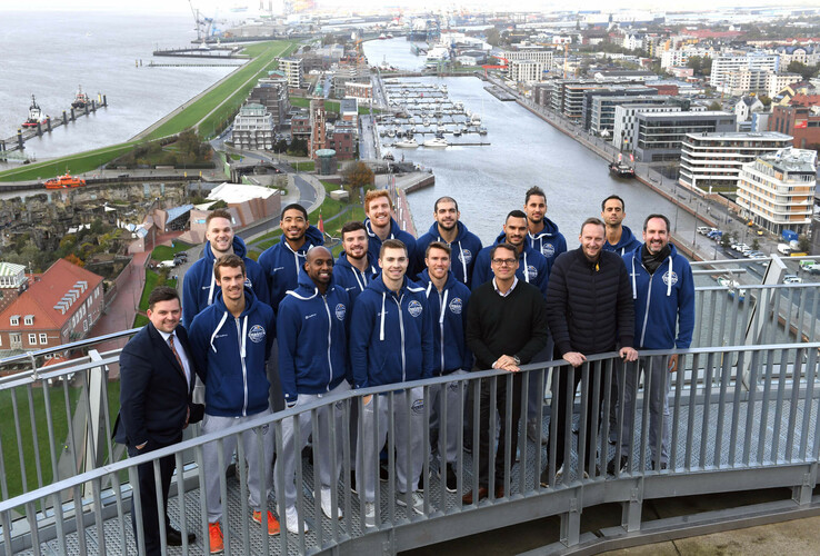 ATLANTIC Hotelgruppe bleibt Team Partner der Eisbären Bremerhaven Gruppe von Personen auf der Aussichtsplattform des ATLANTIC Hotel Sail City mit Blick auf Bremerhaven und den Hafen.