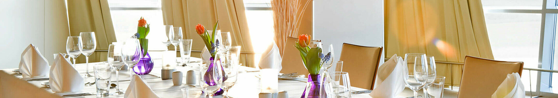 Deck 1 North Elegantly laid table in a bright room with sea view at the ATLANTIC Hotel Sail City, Bremerhaven.