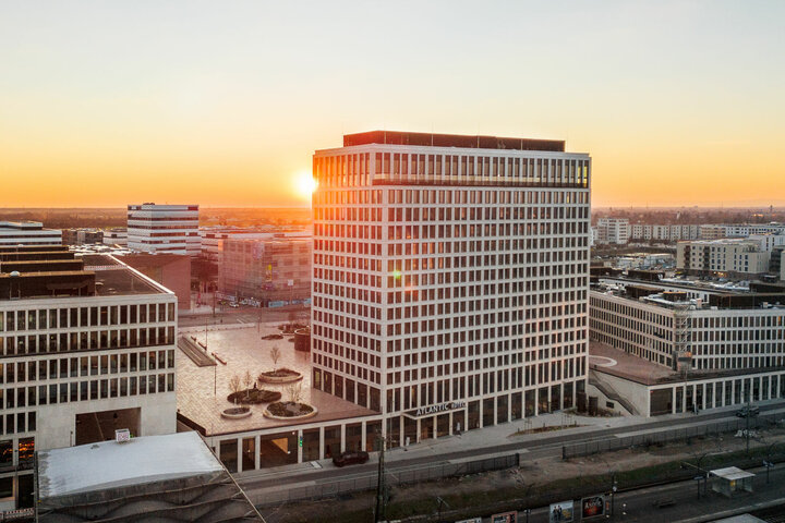 Modernes Hotelgebäude bei Sonnenuntergang, umgeben von städtischer Architektur in Heidelberg.