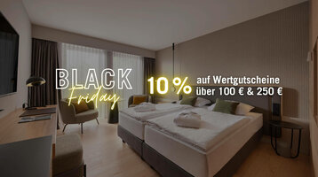 Modern hotel room with double bed, desk, armchair and large window. Text: "Black Friday, 10% off vouchers".
