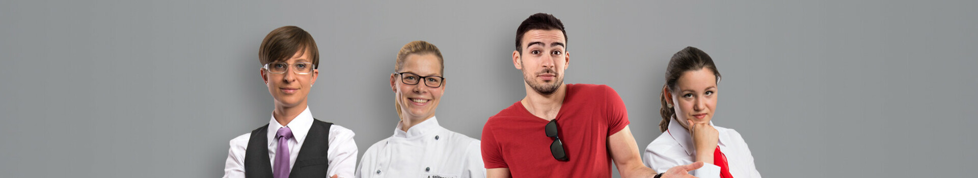 apply in the ATLANTIC Hotel Kiel Four hotel employees in different uniforms in front of a gray background, smiling and friendly.