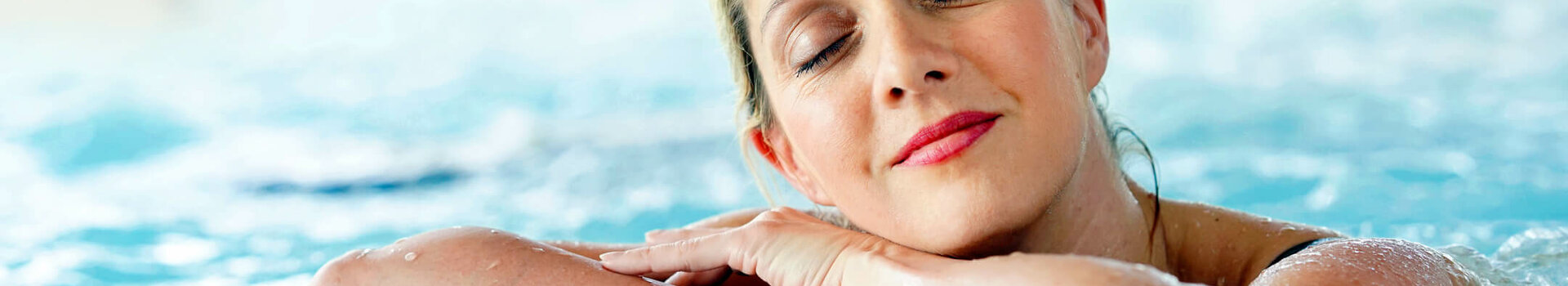 enjoy wellness Woman relaxing in the pool of the ATLANTIC Hotel Wilhelmshaven, head on folded arms, eyes closed.
