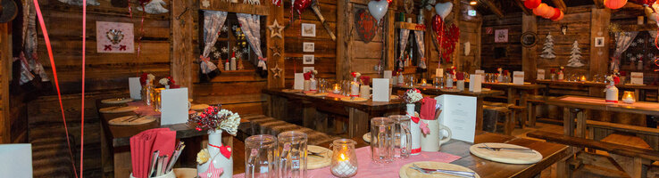 Cozy, rustic restaurant with wooden tables, decorated with red lanterns and heart motifs at the ATLANTIC Grand Hotel Bremen.