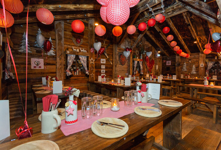 Cozy, rustic restaurant with wooden tables, decorated with red lanterns and heart motifs at the ATLANTIC Grand Hotel Bremen.