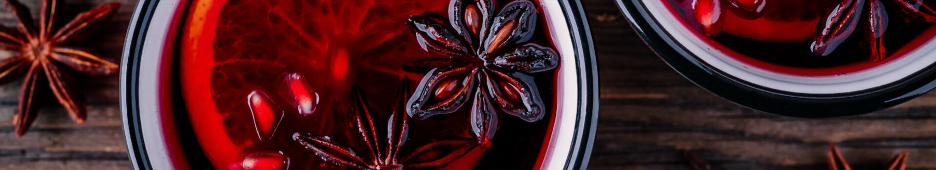 Zwei Becher mit rotem Glühwein und einer Orangenscheibe