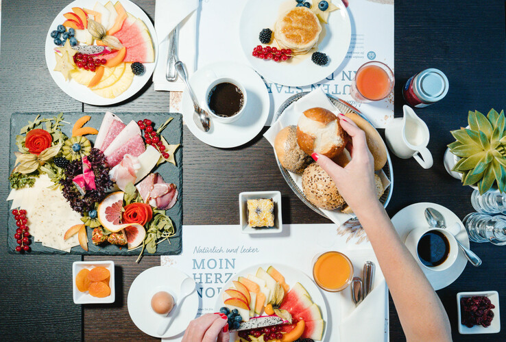 Breakfast table with fruit, cold cuts, bread rolls, coffee and juice in a hotel.