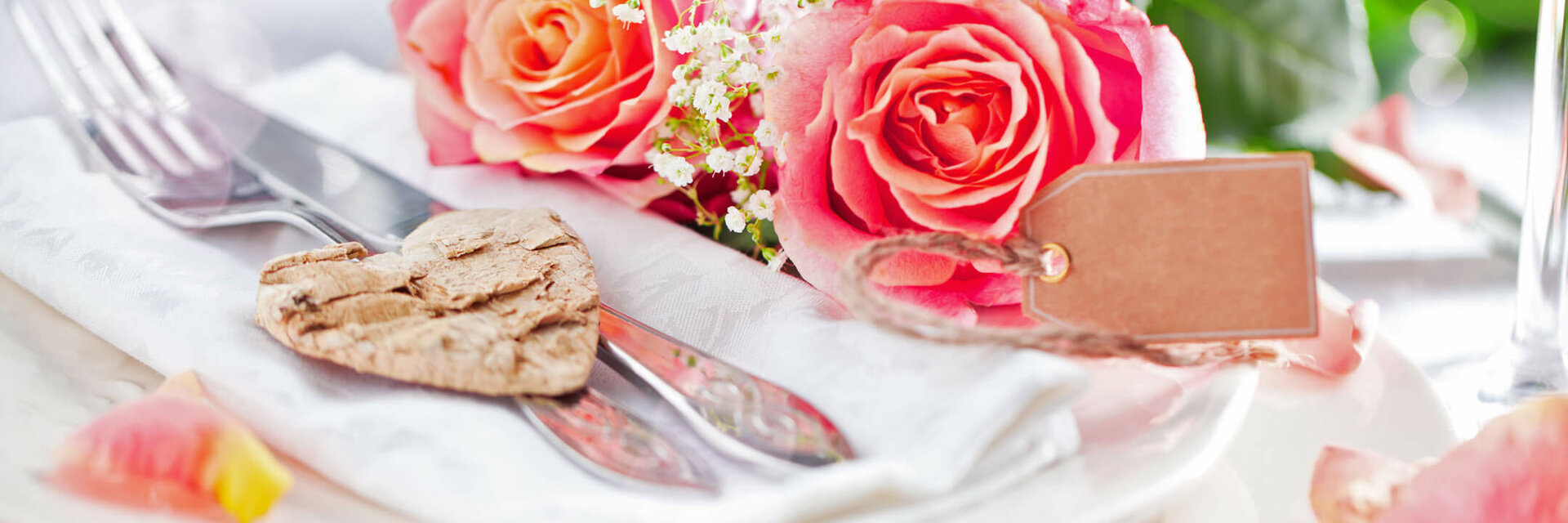 Elegant table decoration with pink roses, cutlery on a napkin and heart pendant at the ATLANTIC Grand Hotel Travemünde.