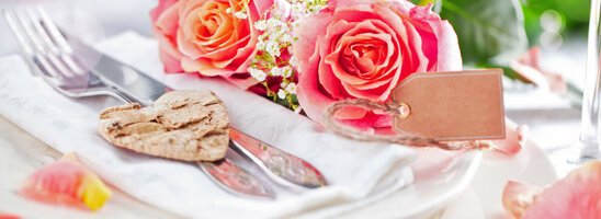 Elegant table decoration with pink roses, cutlery on a napkin and heart pendant at the ATLANTIC Grand Hotel Travemünde.