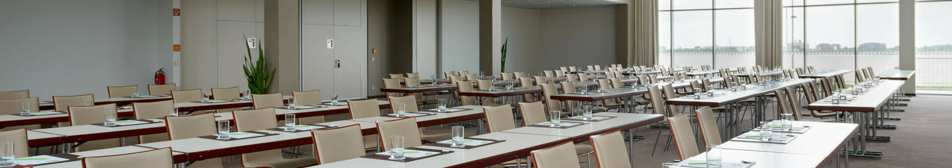 Moderner Konferenzraum im ATLANTIC Hotel Sail City, Bremerhaven, mit Tischen, Stühlen und großen Fenstern.