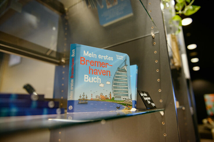 Children's book about Bremerhaven on a glass shelf in the ATLANTIC Hotel Sail City, illustrated with the hotel building.