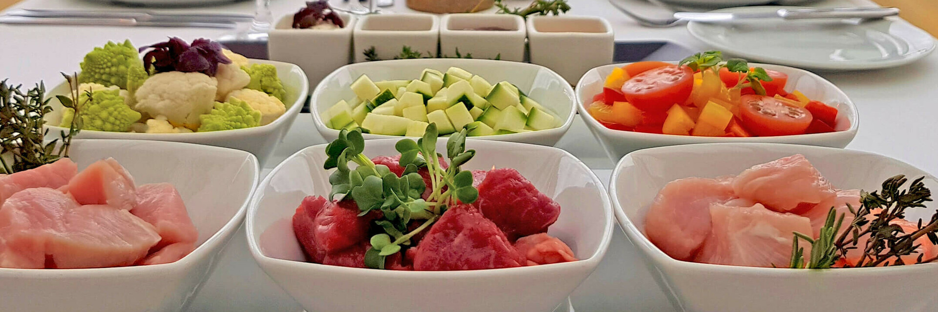 Eleganter Tisch im ATLANTIC Grand Hotel Travemünde mit Meerblick, gedeckt mit frischen Zutaten und Weingläsern.