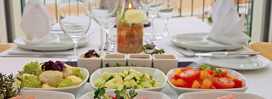 Elegant table at the ATLANTIC Grand Hotel Travemünde with sea view, set with fresh ingredients and wine glasses.