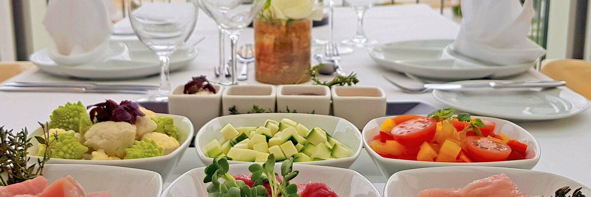 Elegant table at the ATLANTIC Grand Hotel Travemünde with sea view, set with fresh ingredients and wine glasses.