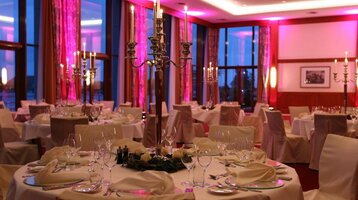 Elegantes Restaurant mit festlich gedeckten Tischen, Kerzenleuchtern und sanfter Beleuchtung im ATLANTIC Hotel Wilhelmshaven.
