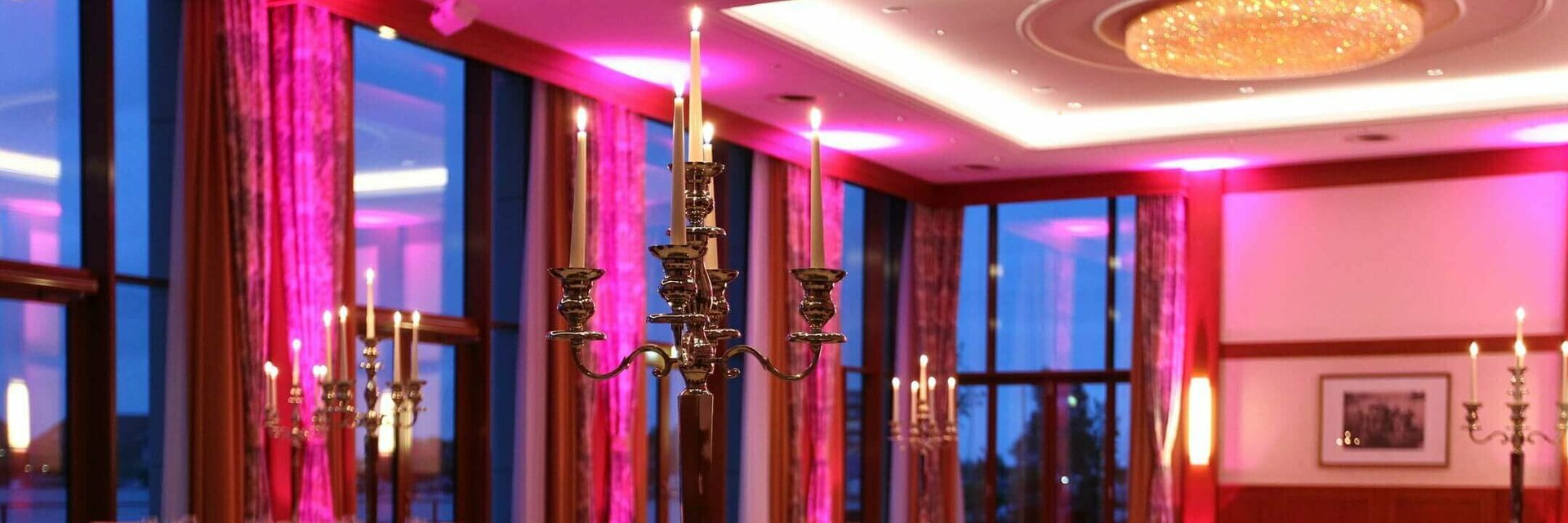 Elegant restaurant with festively laid tables, candlesticks and soft lighting at the ATLANTIC Hotel Wilhelmshaven.