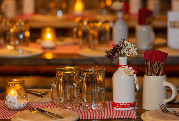 Gemütlich gedeckter Tisch im ATLANTIC Grand Hotel Bremen mit Kerzenlicht, Gläsern und dekorativer Blumenvase.