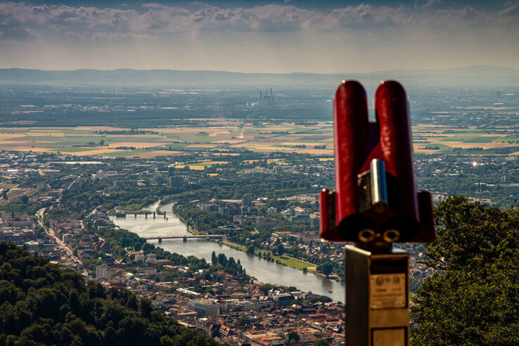 View of a town with a river and fields, in the foreground a pair of red binoculars on a vantage point.