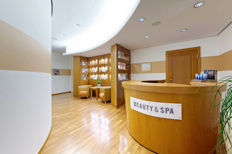 Holzverkleideter Spa-Empfangsbereich mit gemütlichen Sesseln und Regalen voller Produkte.