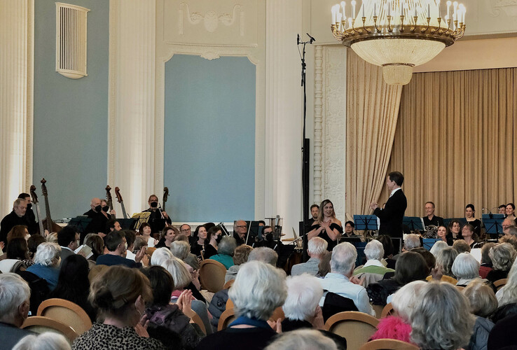 Konzert im ATLANTIC Grand Hotel Travemünde: Orchester spielt vor Publikum in elegantem, klassischem Saal mit großem Kronleuchter.