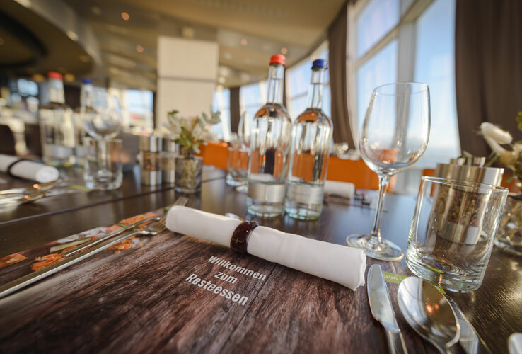 Elegant, laid table in the restaurant of the ATLANTIC Hotel Sail City with glasses and cutlery.