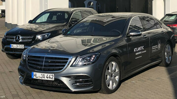 ATLANTIC Grand Hotel Travemünde transfer vehicles Two black limousines with the ATLANTIC Grand Hotel Travemünde logo are parked in front of the hotel entrance.